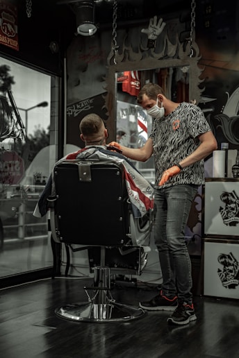 man in black and white shirt sitting on barber chair