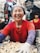A smiling woman enjoying a colorful, neatly packed tiffin box at her office desk.