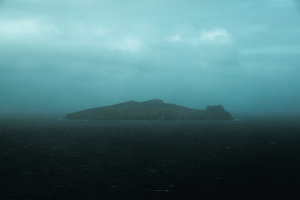 green mountain beside body of water under cloudy sky during daytime