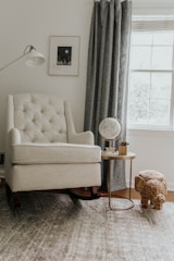 white sofa chair near white window curtain