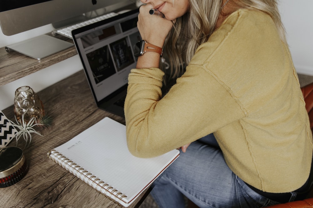 woman in brown long sleeve shirt and blue denim jeans sitting on brown wooden table