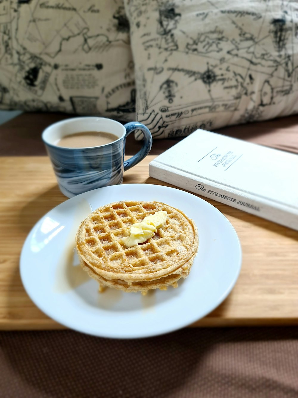 waffle on white ceramic plate beside blue ceramic mug