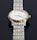 A close-up view of a luxury wristwatch featuring a gold and silver metal band. The watch has a round face with a white dial, golden hour markers, and hands. The brand name and model 'Tissot 1853 Powermatic 80' are visible on the dial.