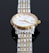 A close-up view of a luxury wristwatch featuring a gold and silver metal band. The watch has a round face with a white dial, golden hour markers, and hands. The brand name and model 'Tissot 1853 Powermatic 80' are visible on the dial.