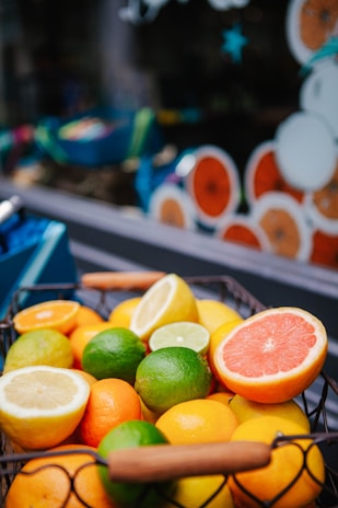 A bunch of vibrant citrus fruits including oranges and lemons on a woven basket.