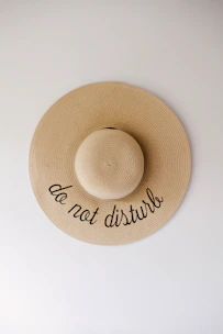 A stylish hat resting on a wooden table, featuring a subtle inspirational phrase embroidered.