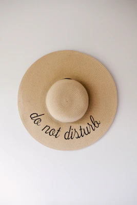 A stylish hat resting on a wooden table, featuring a subtle inspirational phrase embroidered.