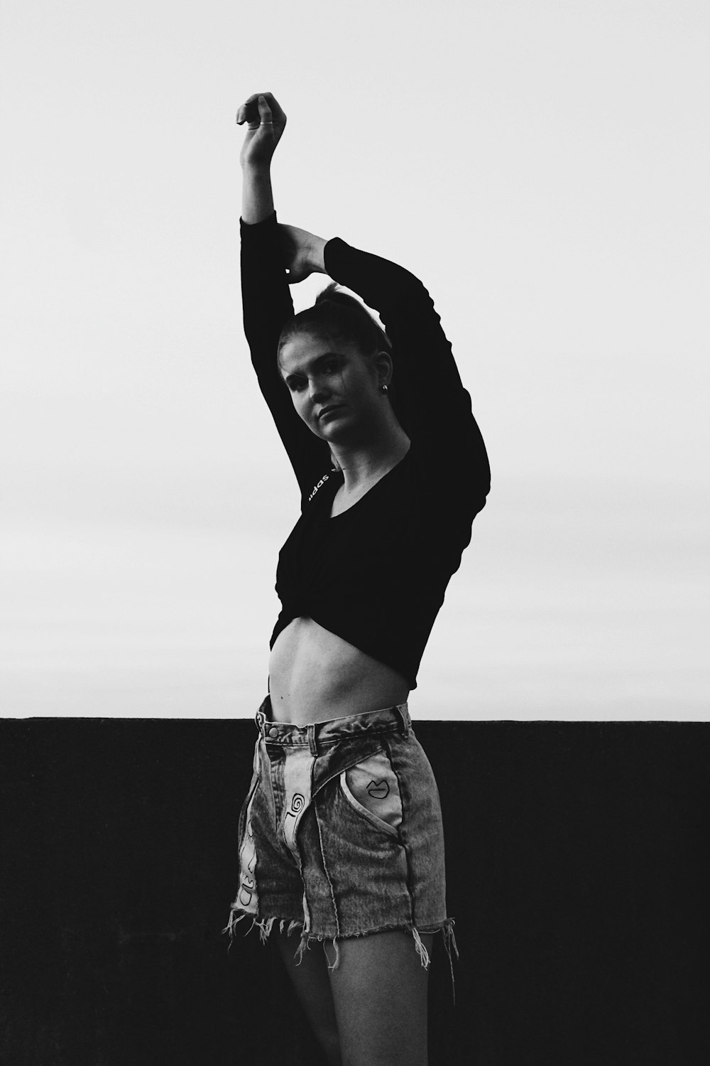 woman in black shirt and gray pants raising her right hand