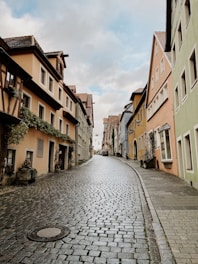 A charming cobblestone street lined with colorful European townhouses under a bright blue sky.