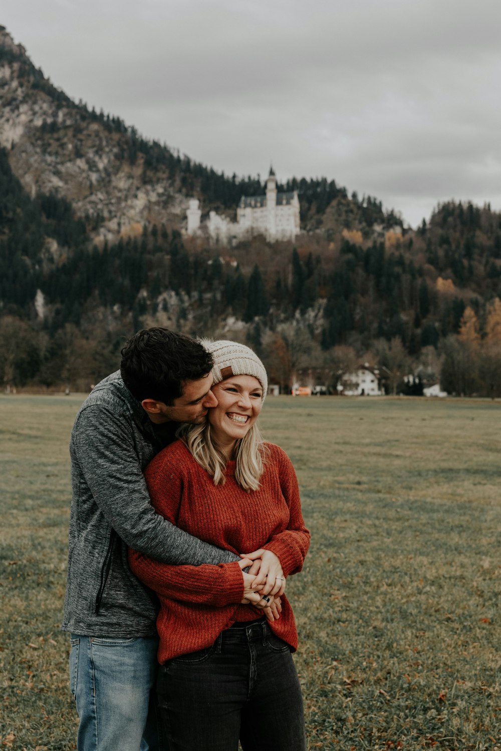 donna in maglione grigio e sciarpa rossa seduta sul campo di erba verde durante il giorno