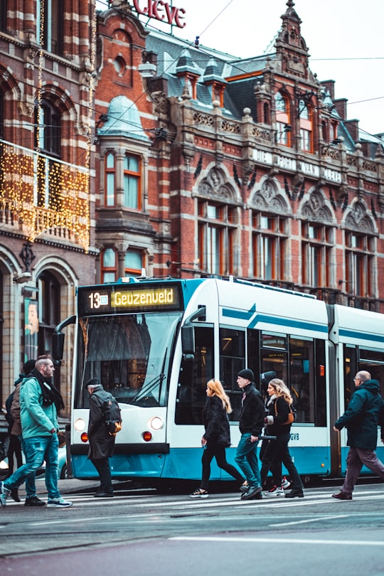 people in blue and white tram in front of brown concrete building during daytime in Hotel Die Port van Cleve Netherlands