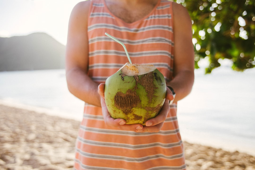 woman in red and white stripe tank top holding green fruit