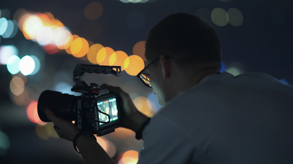 man in white shirt holding black video camera