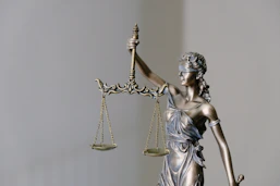 Statue of Lady Justice holding scales with a soft focus background.