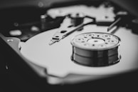 A close-up view of a dismantled hard drive, showing the disk platter and read/write head. The image is in black and white, highlighting the mechanical components and intricate details of the drive.