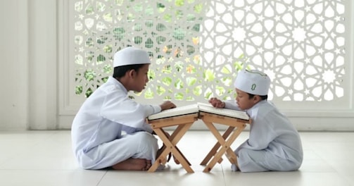 man in white thobe sitting on white floor tiles