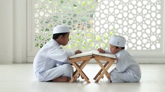 man in white thobe sitting on white floor tiles