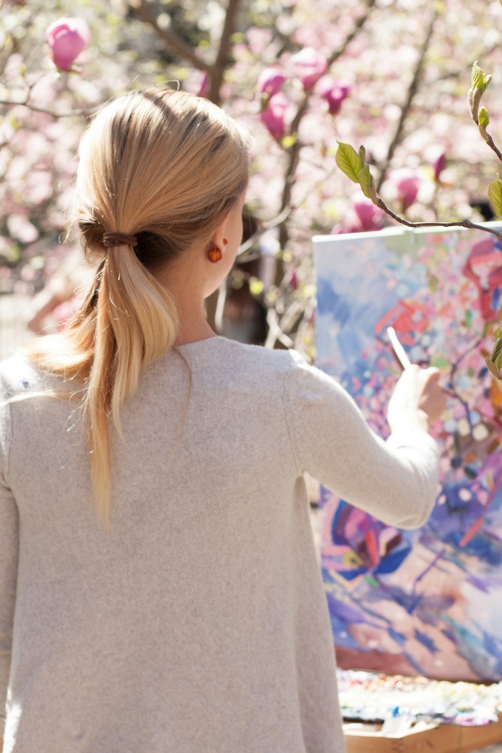 woman in gray long sleeve shirt holding white and pink pen