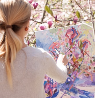 woman in white long sleeve shirt holding white and blue floral painting