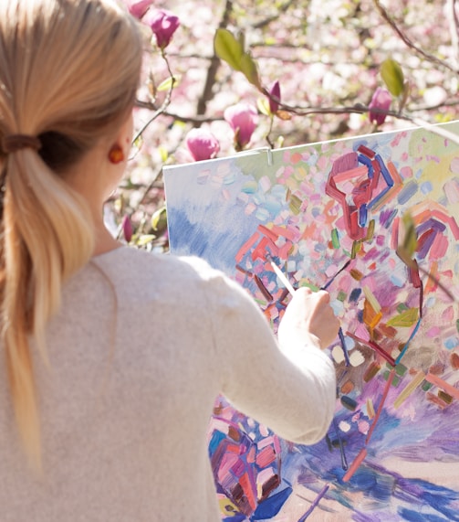 woman in white long sleeve shirt holding white and blue floral painting