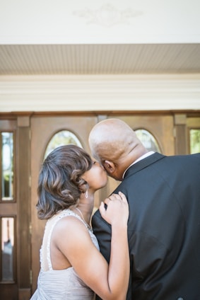 man in black suit kissing woman in white wedding dress