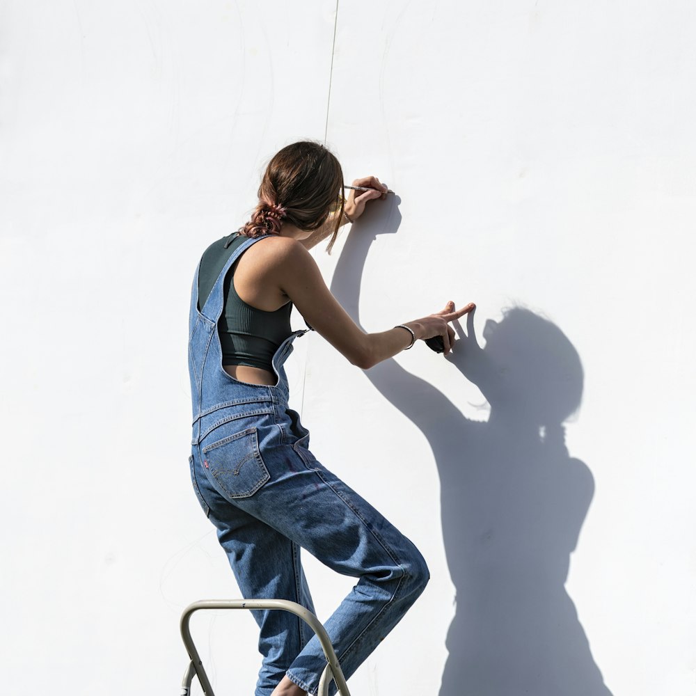 Frau in blauen Jeans und schwarzem Tanktop sitzt auf dem Stuhl