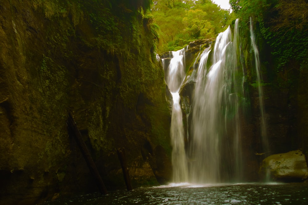 water falls in the middle of green and brown mountain