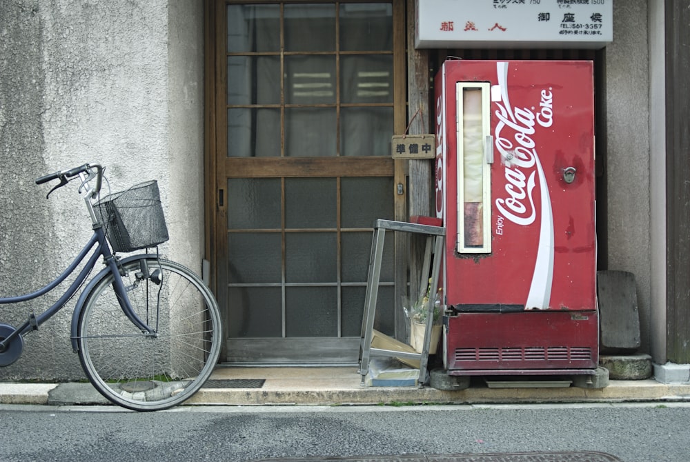 red coca cola vending machine beside brown wooden door