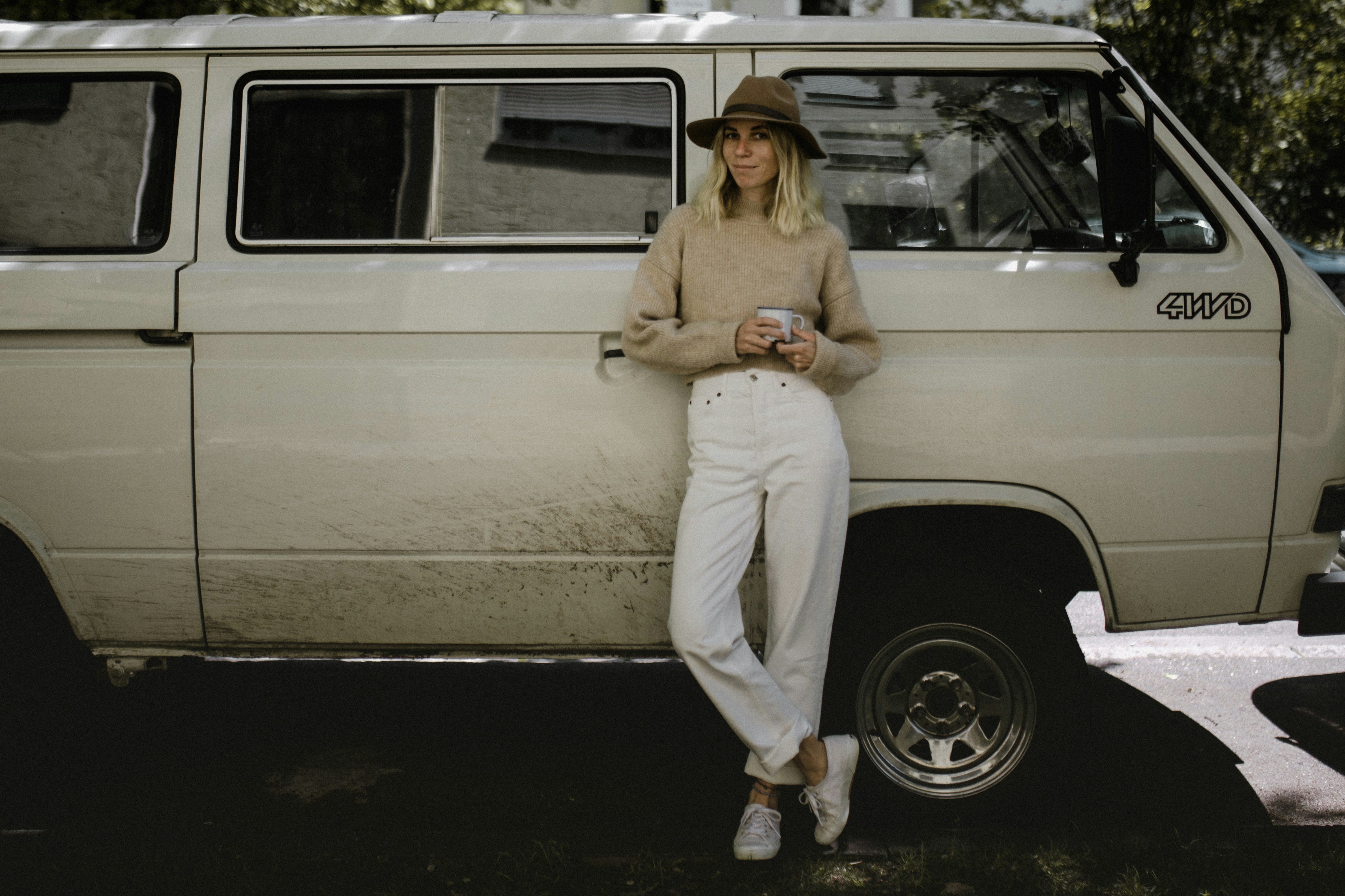 woman in beige long sleeve shirt and white pants sitting on white car