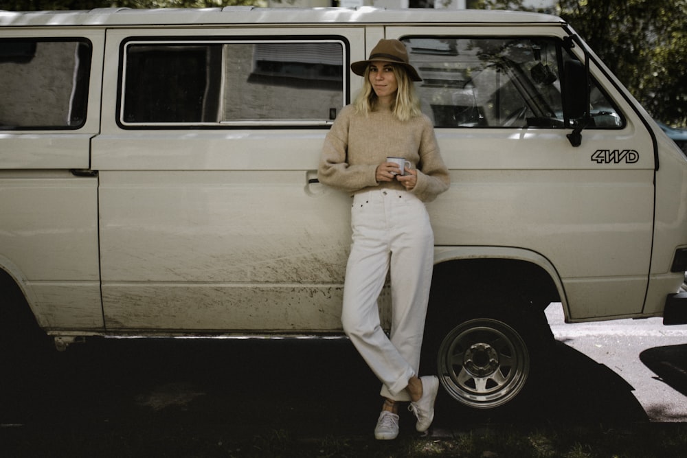 woman in beige long sleeve shirt and white pants sitting on white car