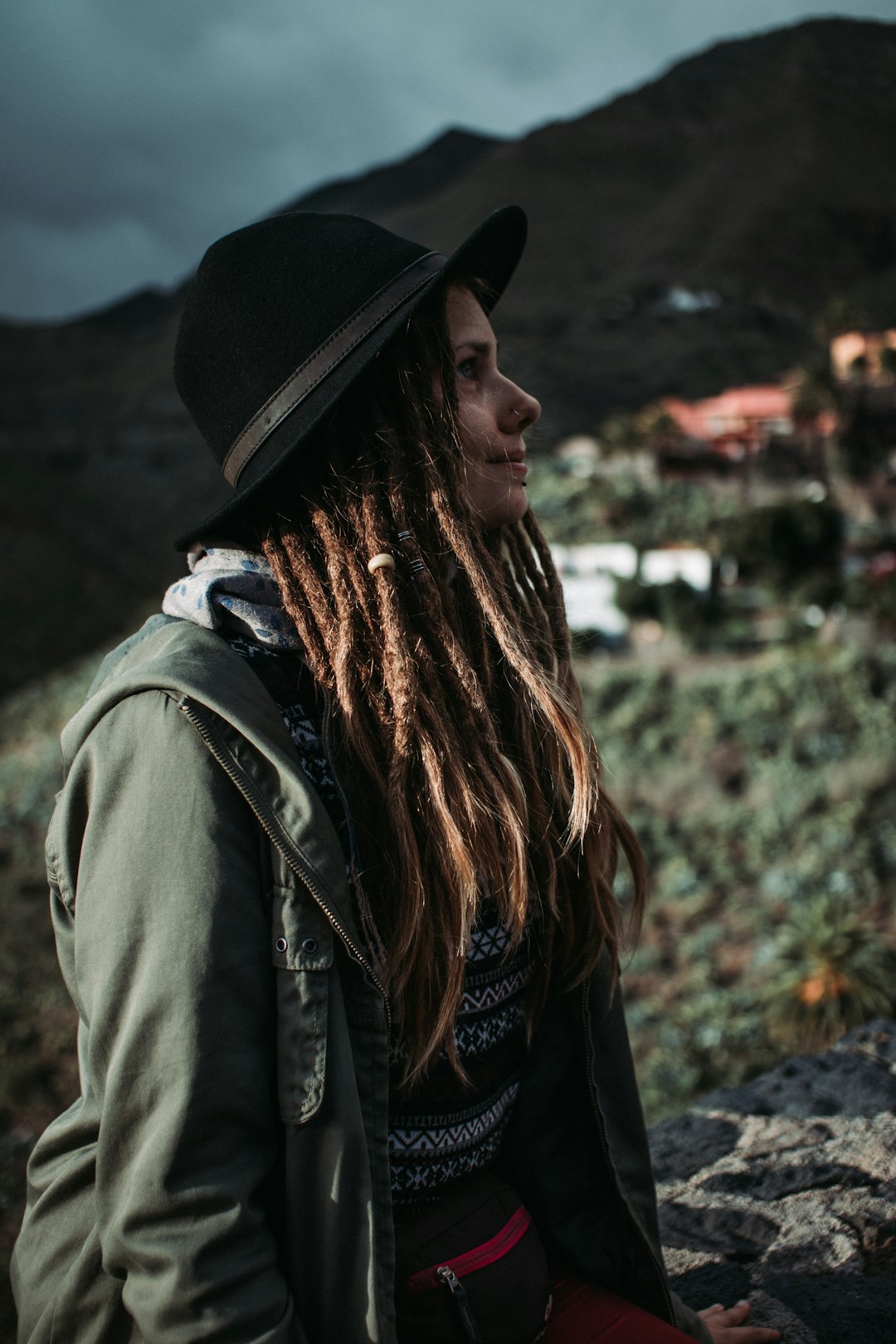 woman in black hat and green jacket standing on ground during daytime