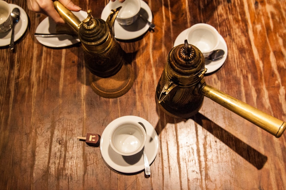 white ceramic teacup on saucer beside brown ceramic teapot