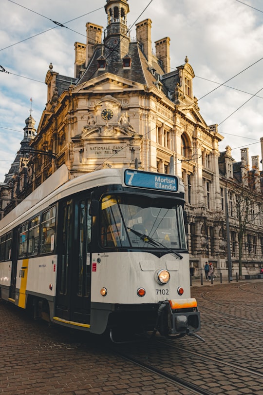 white and yellow tram in front of brown concrete building in Antwerpen Belgium