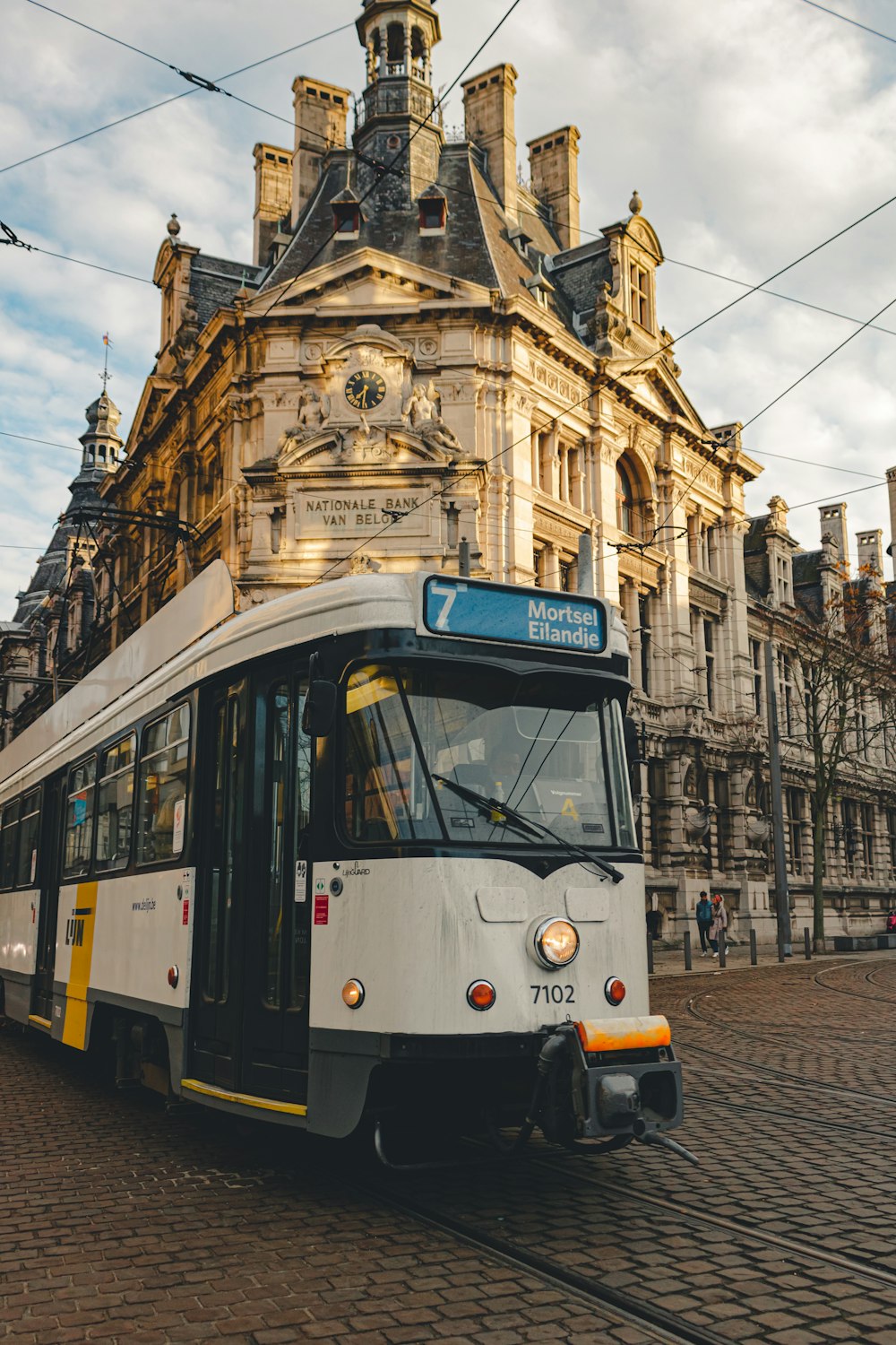 white and yellow tram in front of brown concrete building