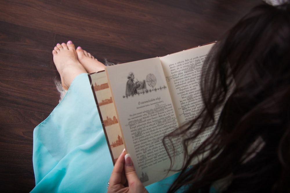 woman in blue long sleeve shirt holding white book