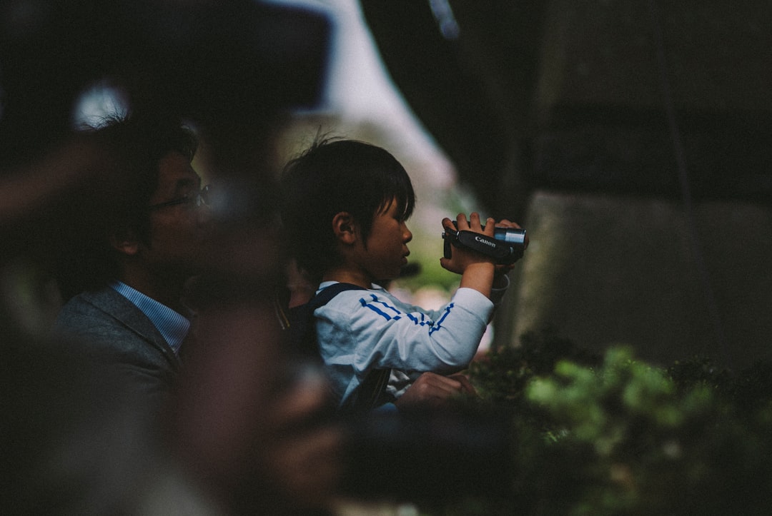 boy in blue dress shirt holding black dslr camera