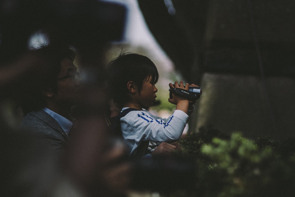 boy in blue dress shirt holding black dslr camera