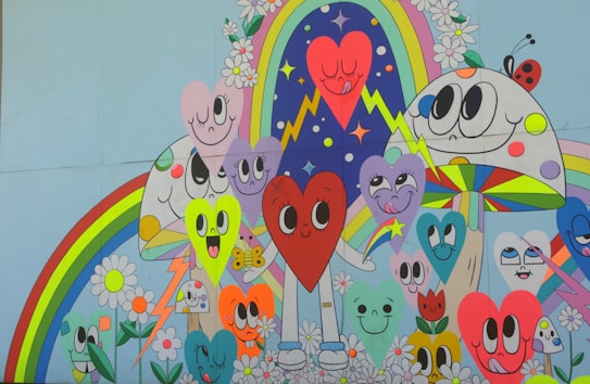 A colorful mural featuring cartoon-style hearts with expressive faces surrounded by various whimsical elements like flowers, rainbows, and a large mushroom. The characters have large, animated eyes and playful expressions, and there are lightning bolts and stars in the background.