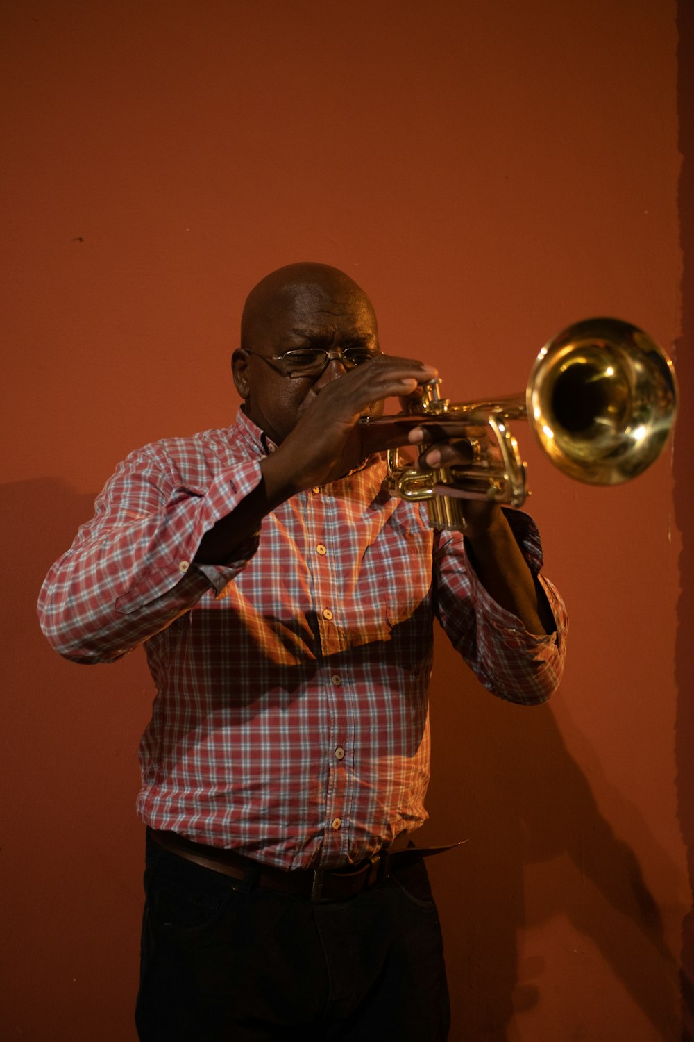 man in red and white plaid button up shirt playing trumpet