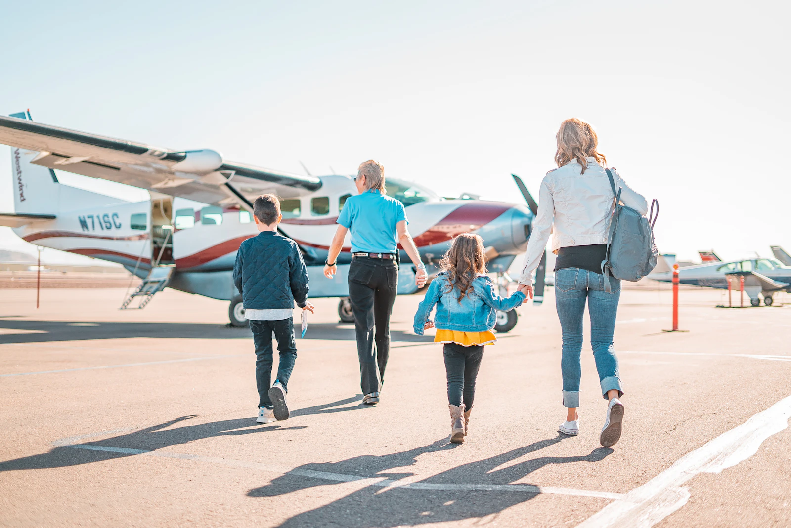An adult and a child walk together through an airport terminal with travel bags.