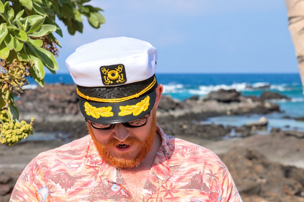 man in pink and white floral shirt wearing white and yellow cap