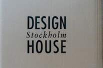 A cardboard background with the words 'DESIGN Stockholm HOUSE' printed in bold black letters.