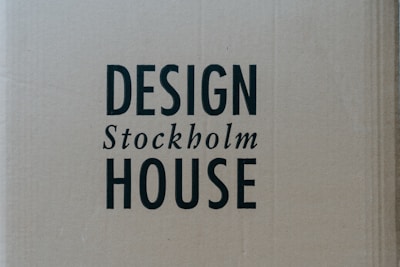 A cardboard background with the words 'DESIGN Stockholm HOUSE' printed in bold black letters.