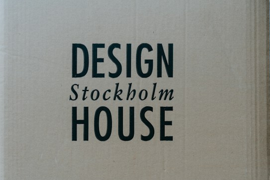 A cardboard background with the words 'DESIGN Stockholm HOUSE' printed in bold black letters.
