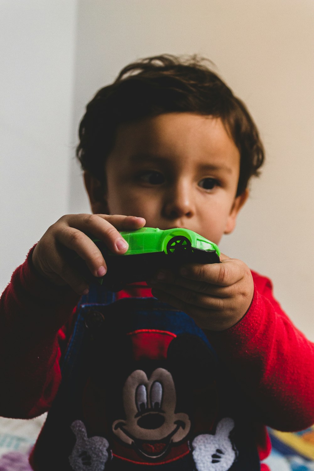 boy in red and black long sleeve shirt holding green plastic toy gun