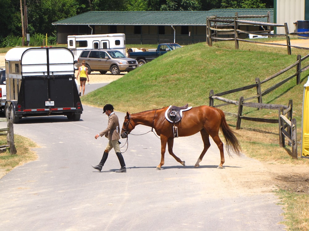 man in green shirt and black pants riding brown horse during daytime