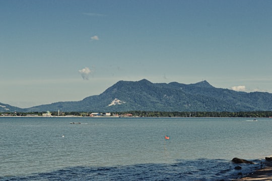 people riding boat on sea near mountain under blue sky during daytime in Pantai Merdeka Malaysia