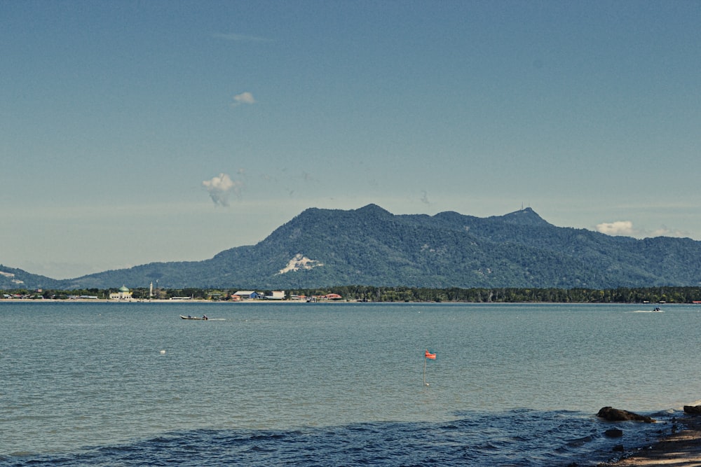 people riding boat on sea near mountain under blue sky during daytime