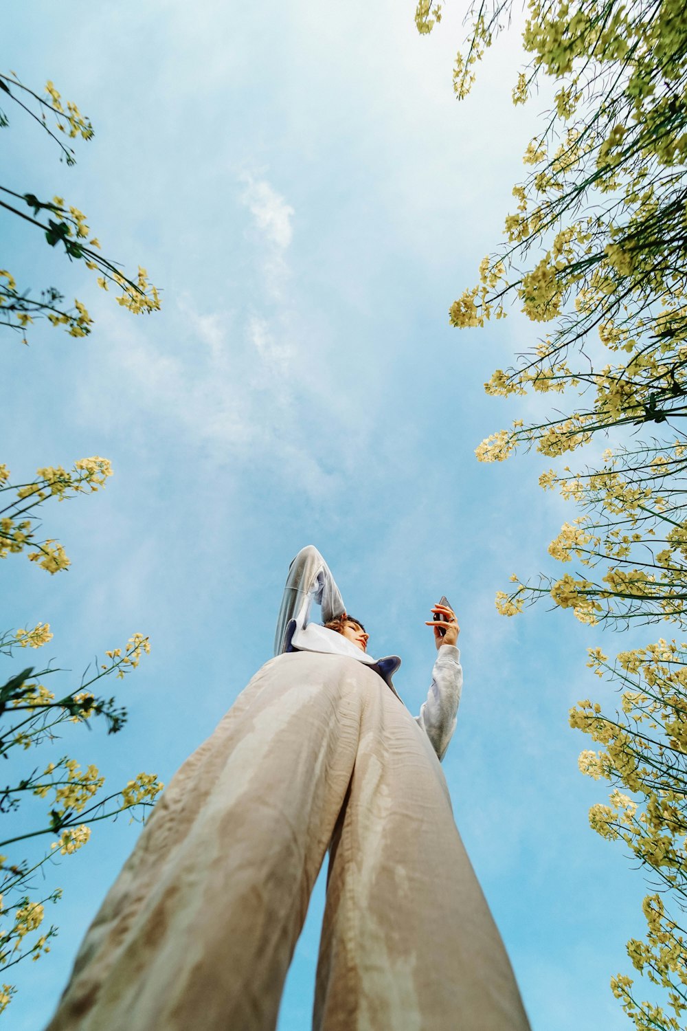 low angle photography of woman in white dress standing under green tree during daytime