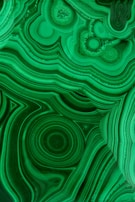 A cluster of deep green malachite stones with distinctive swirling patterns.